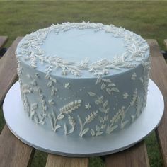 a blue frosted cake sitting on top of a wooden table next to a field