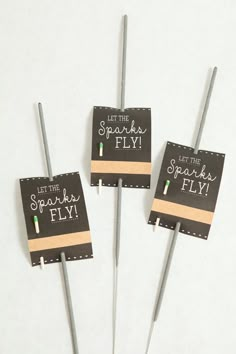 three small toothpicks sitting on top of each other in front of a sign that says let the sparkle fly