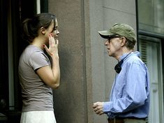 a woman talking on her cell phone next to an older man standing in front of a building