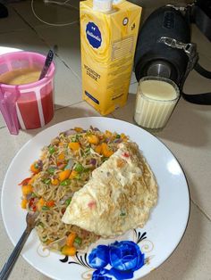 a white plate topped with food next to a cup of milk and a carton of orange juice