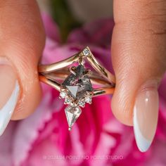 a woman's hand holding an engagement ring with two diamonds on the top and bottom