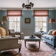 a living room with two couches, chairs and a coffee table in front of windows