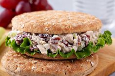 a chicken salad sandwich with lettuce and cranberries on a cutting board