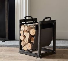 a stack of logs sitting in a black container on top of a wooden floor next to a fireplace