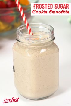 a glass jar filled with frosted sugar next to a bowl of fruit and a striped straw