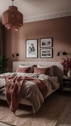 a bedroom with pink walls and bedding in the center, two pictures on the wall