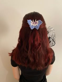 a woman with long red hair wearing a blue butterfly clip