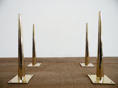 three metal poles are standing in the middle of a wood floor with two white walls behind them