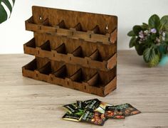 a wooden rack with six compartments and four packets on the floor next to it, near a potted plant