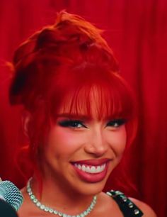 a woman with red hair is smiling and holding a microphone in front of her face