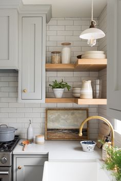 a white kitchen with open shelving above the stove