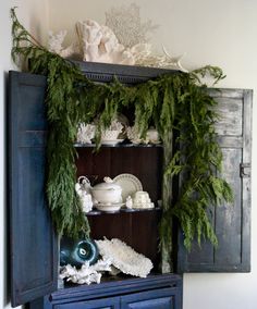 an old china cabinet is decorated with greenery and other things to decorate on it