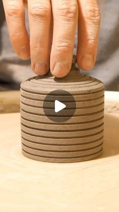 a person is making a stack of brown paper coasters with their thumb on the top