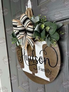 a door hanger that says, hudson family on it with a bow and greenery