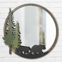 there is a mirror with a bear and trees on it in front of a brick wall