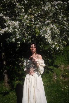 a woman in a white dress is posing for the camera with her hands on her chest