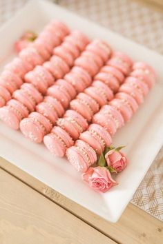 there is a white plate with pink macaroons on it