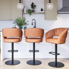 two brown leather stools sitting in front of a kitchen counter