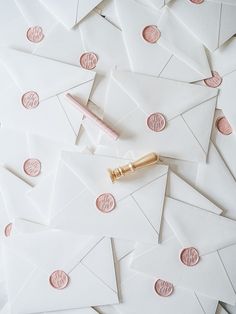 some white envelopes with pink wax stamping and a pen on top of them