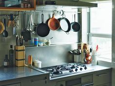 pots and pans are hanging on the wall above the stove in this small kitchen