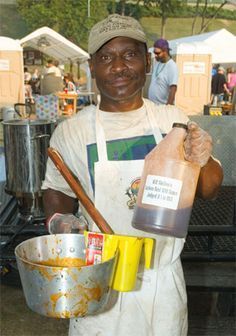 a man in an apron holding a bottle and mixing bowl