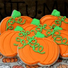 four decorated pumpkin cookies sitting on top of a table