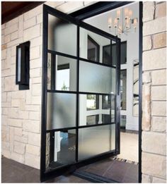 an open glass door in front of a brick wall with a chandelier hanging from the ceiling