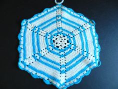 a blue and white crocheted ornament hanging on a black table top