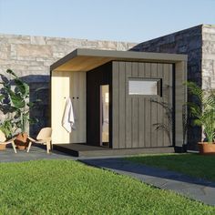 a small wooden shed sitting on top of a lush green field next to a stone wall