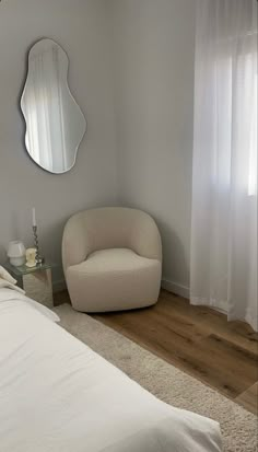 a bedroom with a white bed, mirror and chair in the corner on the wall