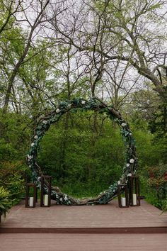 an outdoor ceremony setup with greenery and candles in the center, surrounded by trees