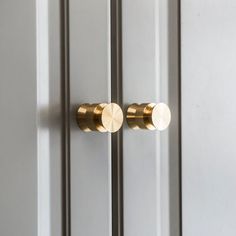 two brass knobs on the side of a white door