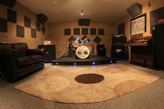 a living room filled with lots of furniture and musical instruments on top of a rug