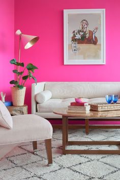 the living room is painted bright pink and has two chairs, a coffee table, and a painting on the wall