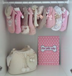 there are many baby clothes hanging on the rack next to a book and booties