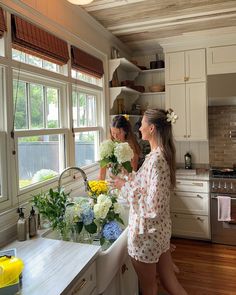 two women are in the kitchen preparing flowers