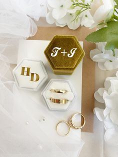 wedding rings, ring box and flower bouquet on top of a piece of brown paper