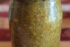 a jar filled with green stuff sitting on top of a wooden table