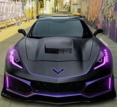 a black sports car with purple lights on it's hood parked in front of a graffiti covered wall