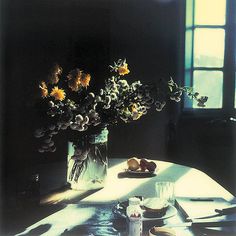 a vase filled with yellow flowers sitting on top of a table next to a window