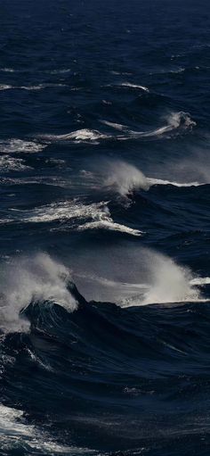 some very big waves in the ocean with dark blue water and white caps on them