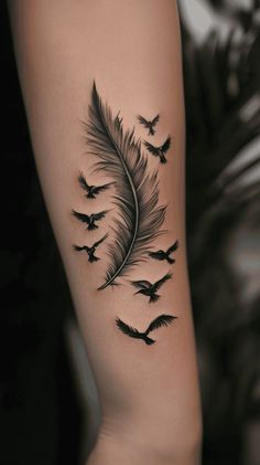 a woman's arm with birds flying in the sky and a feather tattoo on it