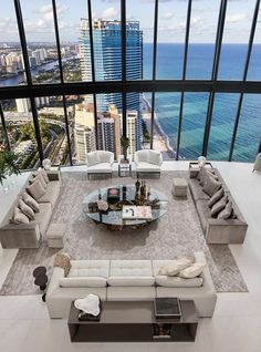 a living room filled with lots of furniture next to a large window overlooking the ocean