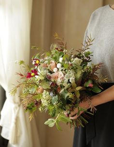 a woman holding a bouquet of flowers in her hands