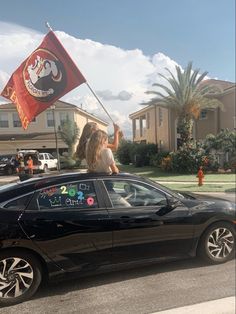 a woman waving a flag on top of a car