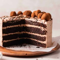 a chocolate cake with white frosting and balls of chocolate on top is sitting on a plate