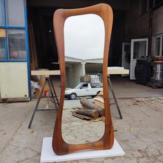 a large wooden mirror sitting on top of a white stand in front of a building