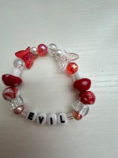 a red and white beaded bracelet with the word evil written in letters on it