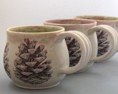 three coffee mugs with designs on them sitting side by side