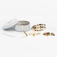 an assortment of beads and tins on a white surface